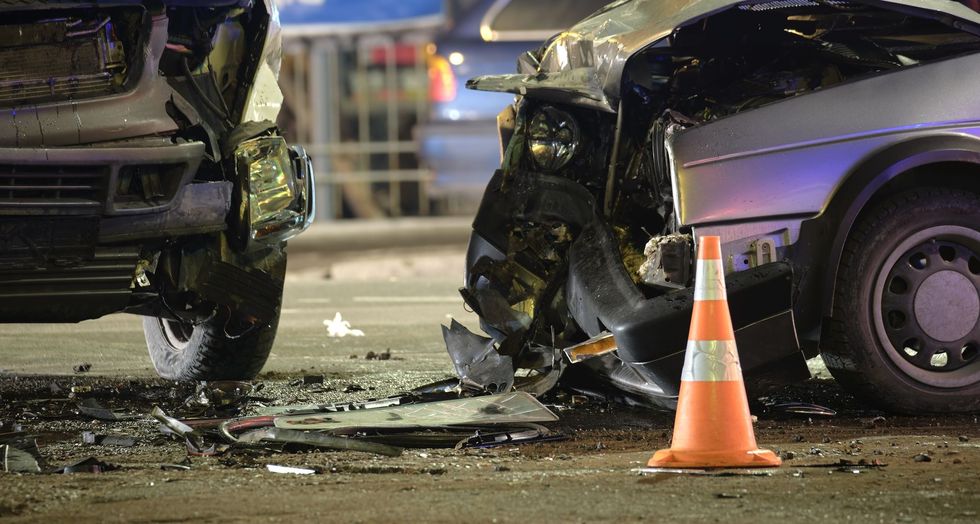 A car accident on a city street with a traffic cone in the foreground.