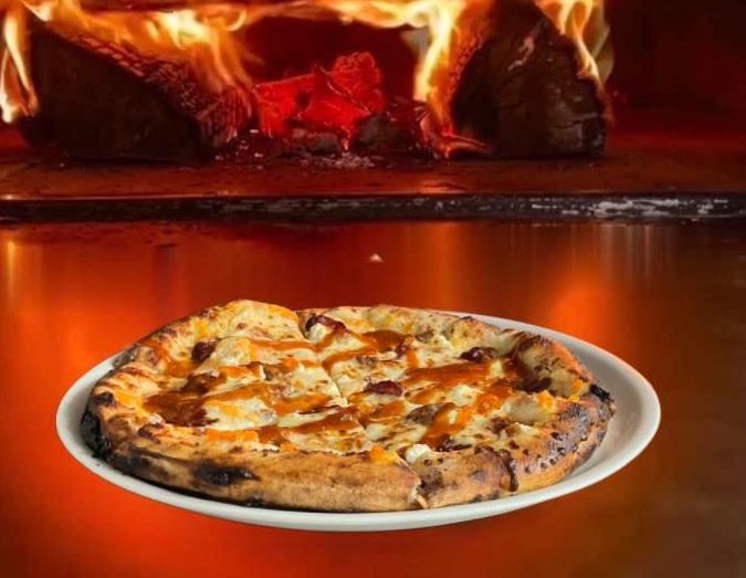 A pizza is being cooked in a wood fired oven