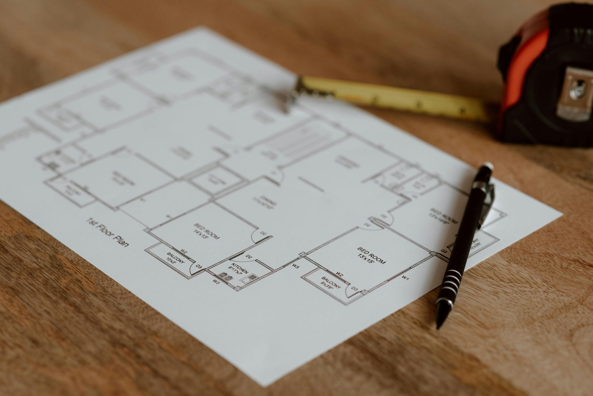 Blueprint floor plan on a table with a pencil and measuring tape nearby.