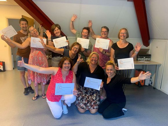 Een groep mensen poseert voor een foto terwijl ze papieren in hun handen houden.