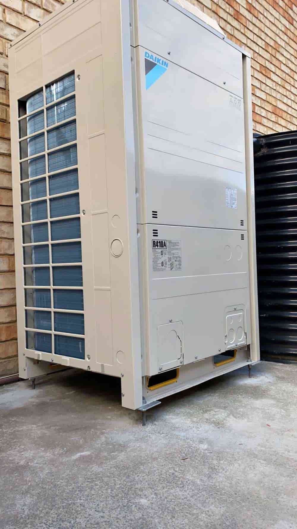 A Large Air Conditioner is Sitting Outside of a Brick Building — Cool Heat Air Conditioning in Albion Park, NSW