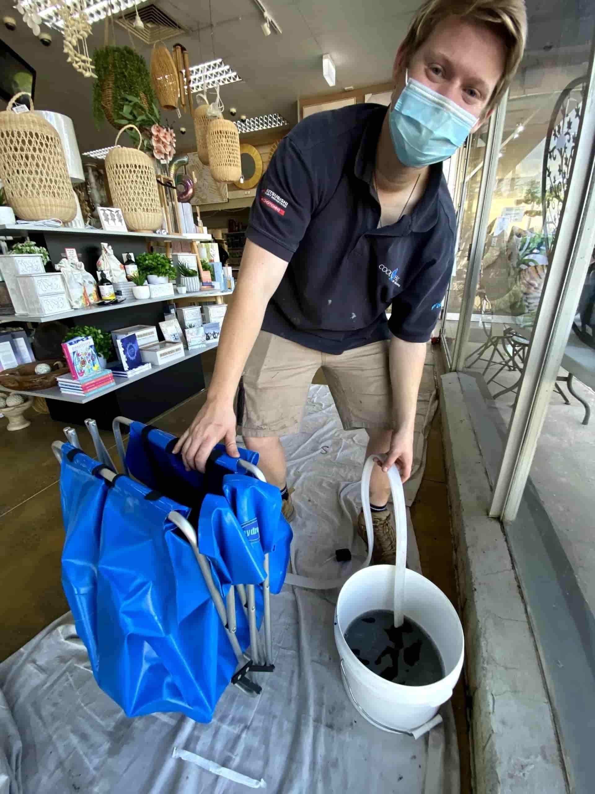 A Person is holding a bucket of dirty water — Cool Heat Air Conditioning in Gerringong, NSW
