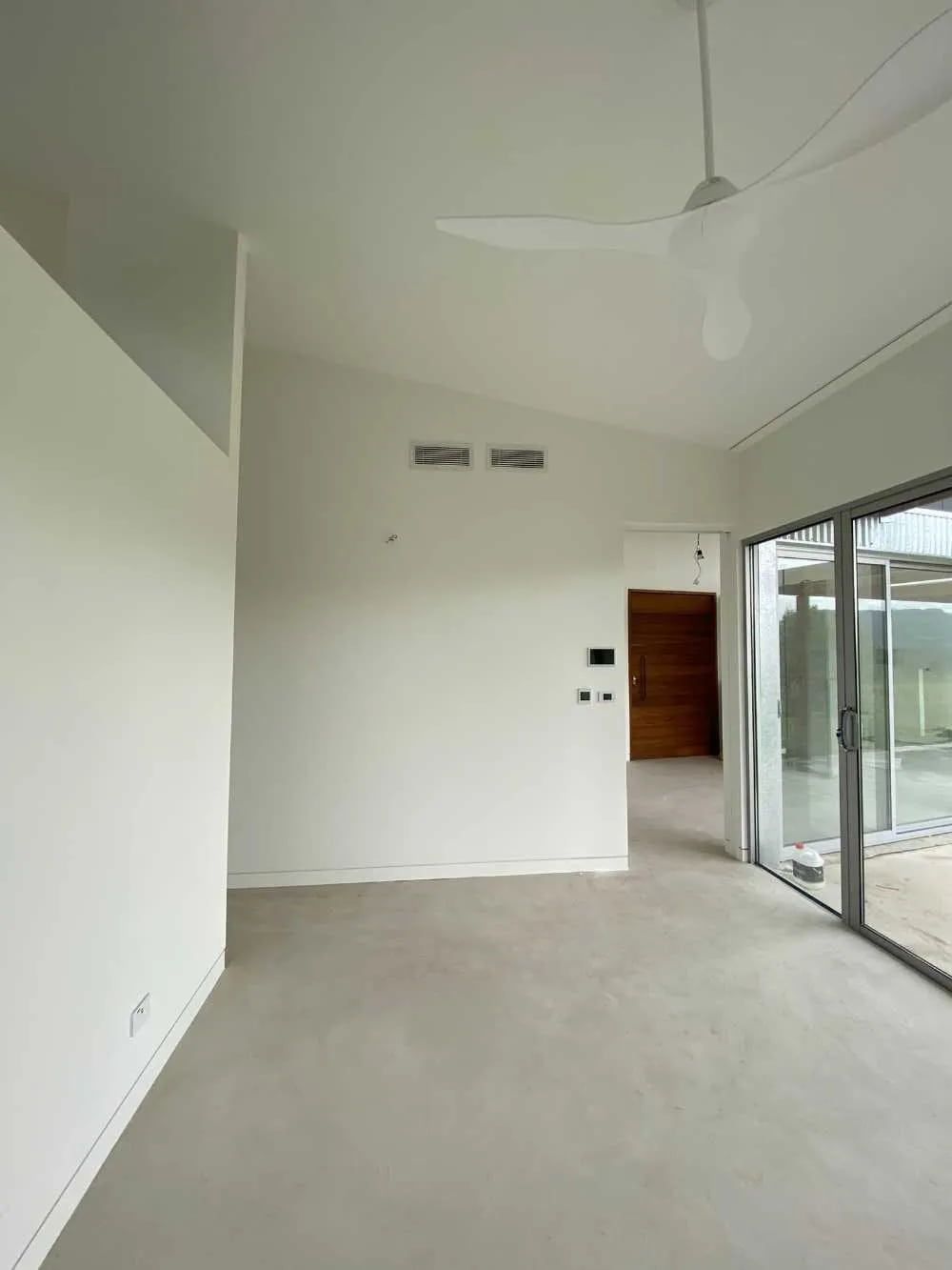 An Empty Living Room With a Ceiling Fan and Large Windows — Cool Heat Air Conditioning in Southern Highlands, NSW