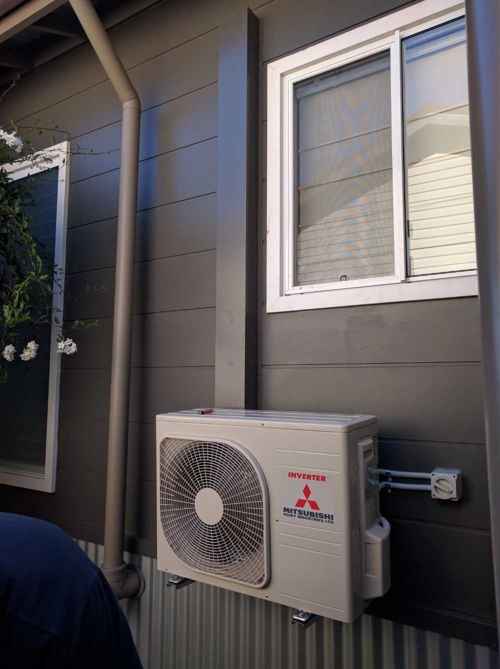 A Mitsubishi Air Conditioner is Mounted on the Side of a Building — Cool Heat Air Conditioning in Albion Park, NSW