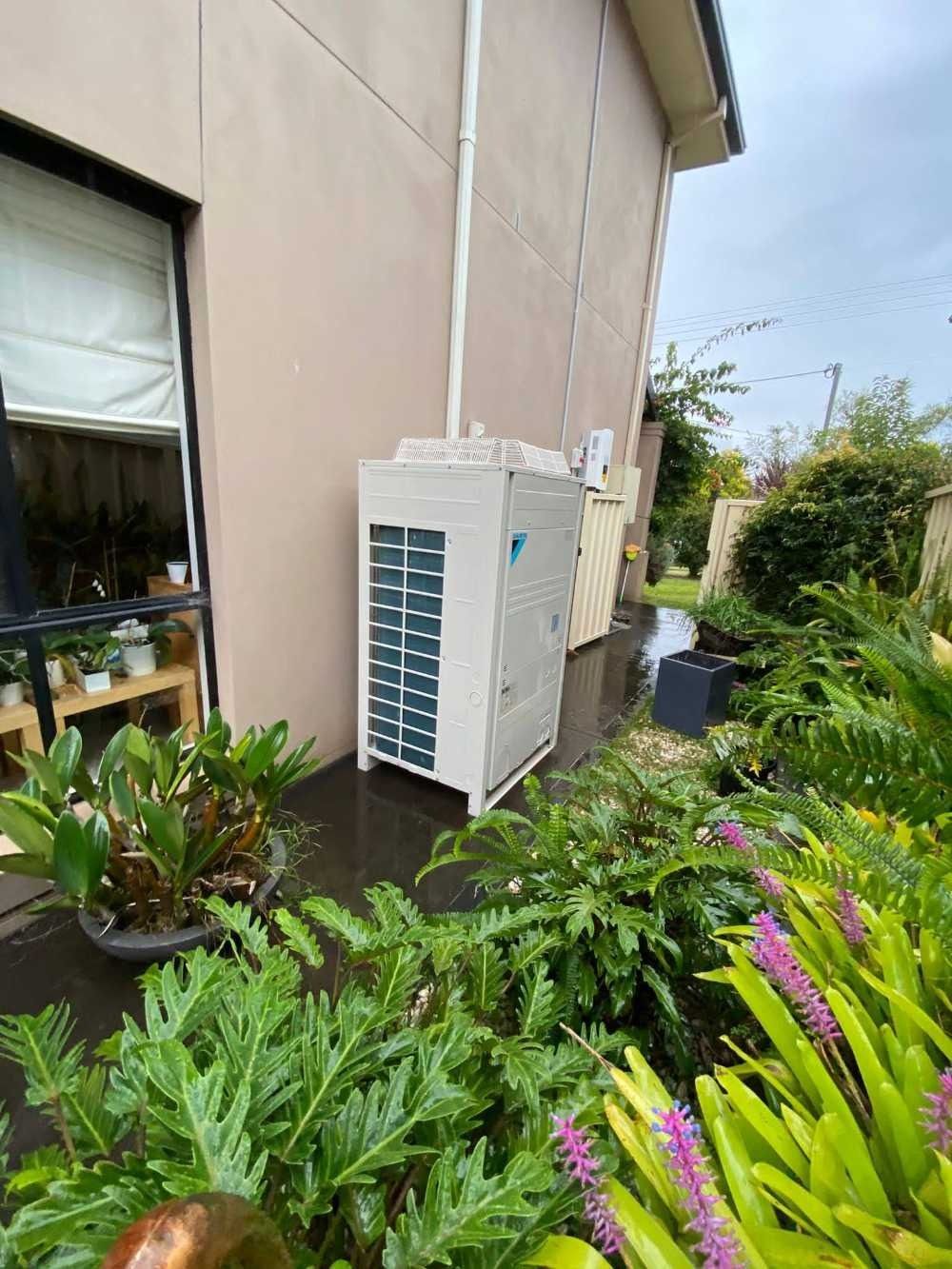 A Large Air Conditioner is Sitting Outside of a House — Cool Heat Air Conditioning in Albion Park, NSW