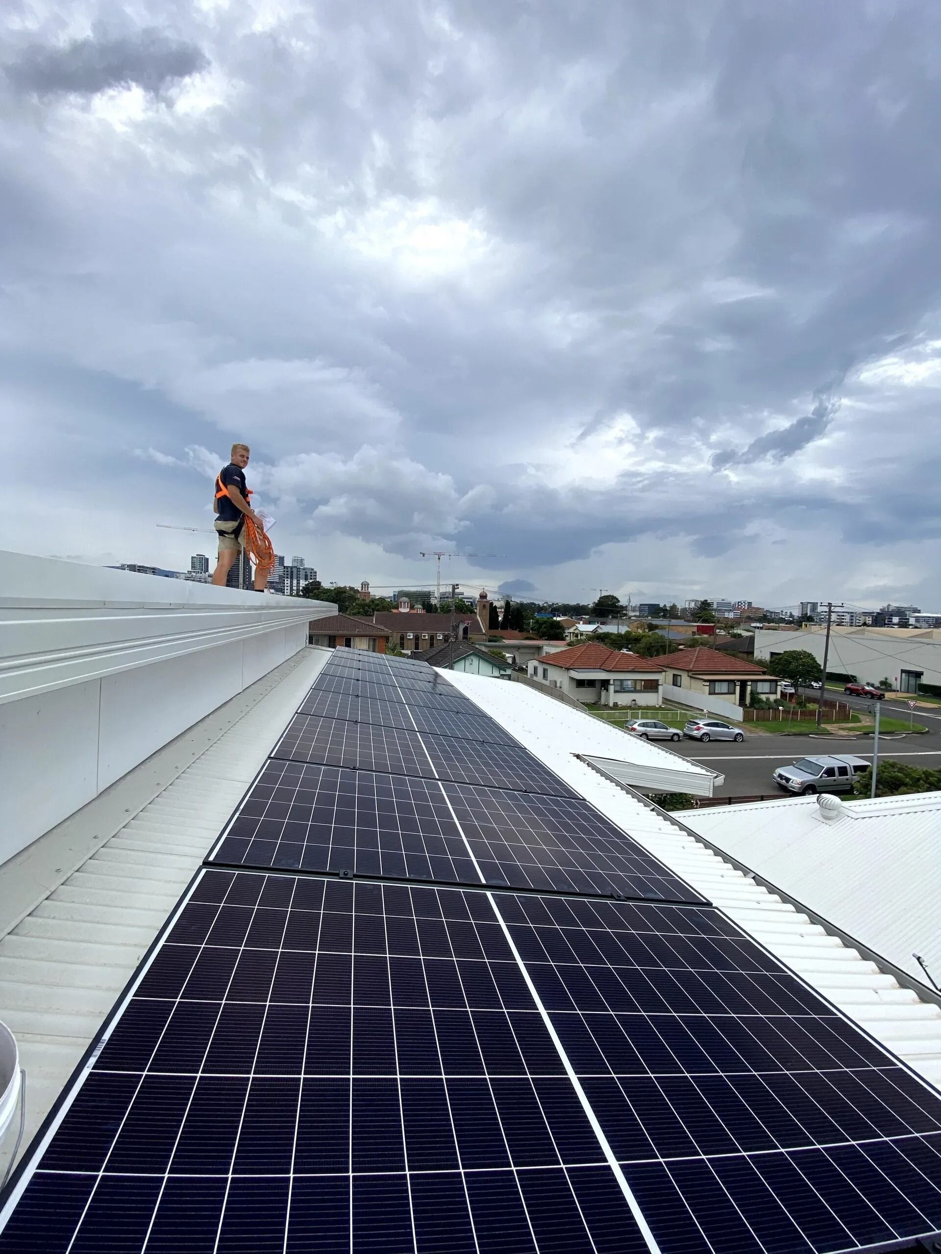 A man i standing on a roof with solar panels — Cool Heat Air Conditioning in Albion Park, NSW