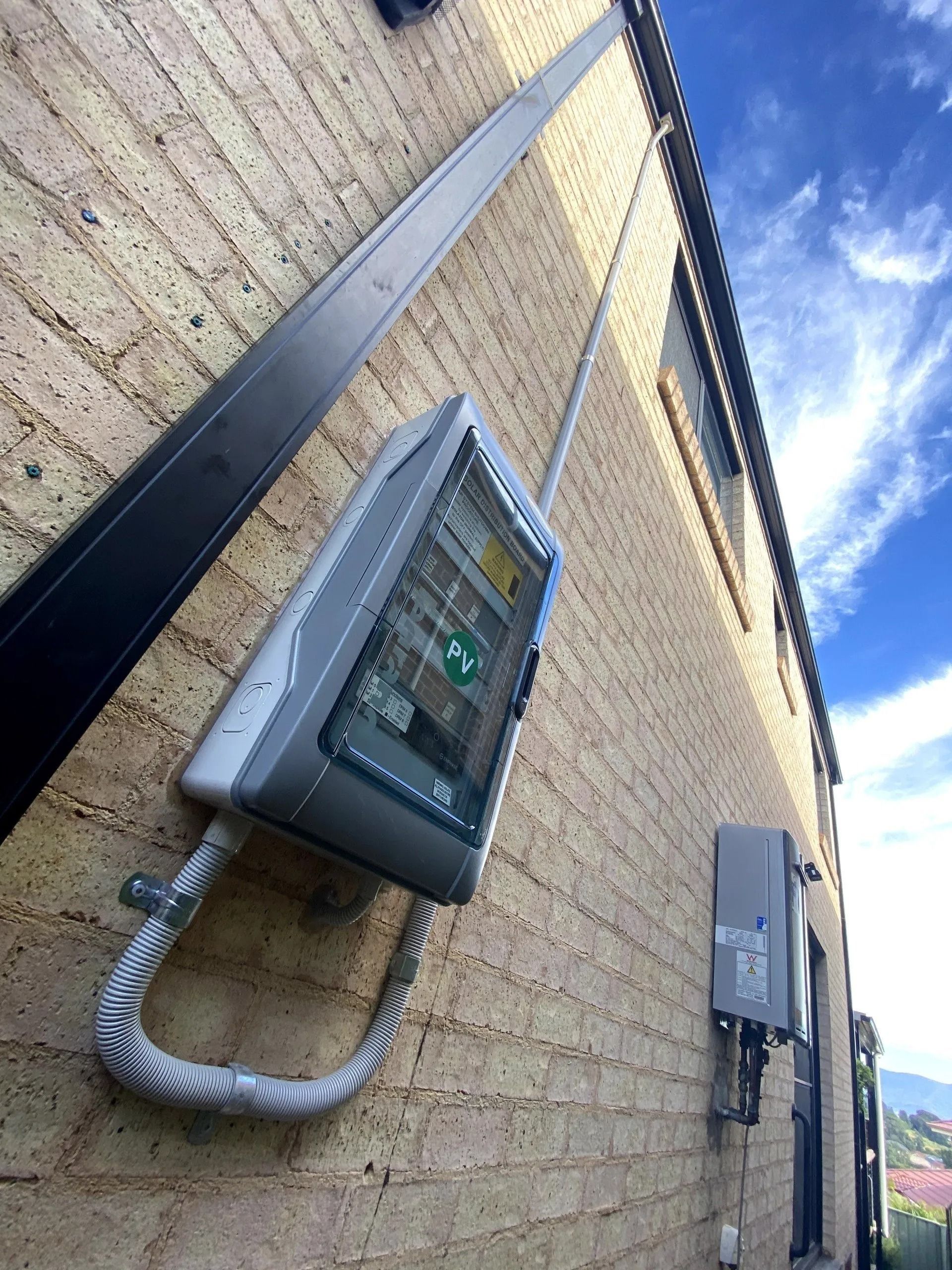A house with a brick wall has a switchboard attached to it — Cool Heat Air Conditioning in Albion Park, NSW