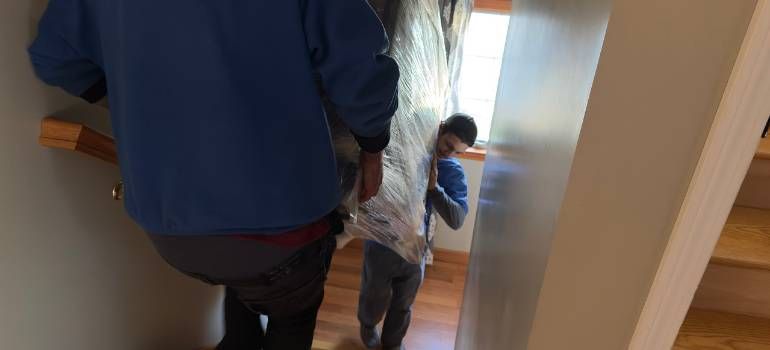 Two people walking down a stairwell, one in a blue jacket and one in a gray hoodie.