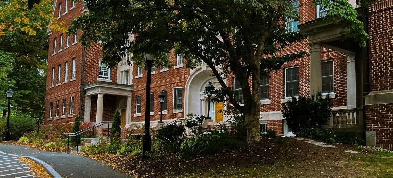 Brick apartment building with white columns and autumn trees along a wet street