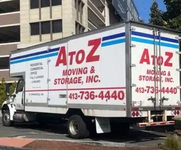 AtoZ Moving & Storage truck parked on a city street, white with red and blue lettering.