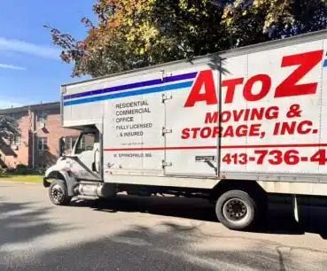 AtoZ Moving & Storage truck parked on a street beside a building, with large red and blue logo text.