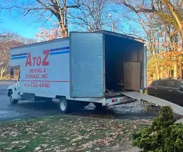AtoZ moving truck parked on a driveway with its rear cargo door open in a suburban yard