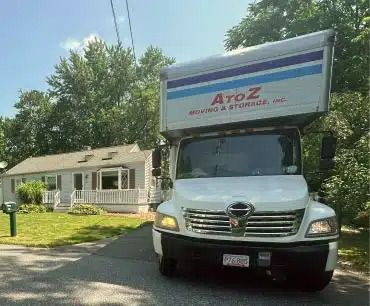 White A-to-Z moving truck parked in front of a small house on a sunny street