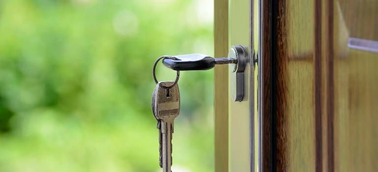 Keys in a door lock on a wooden door, with a green blurred background