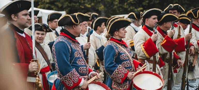 Musicians in red-and-blue traditional uniforms playing drums and brass instruments in a parade
