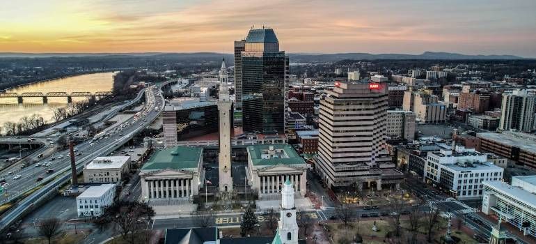 Sunset aerial view of a city skyline with a river, bridge, and tall office buildings