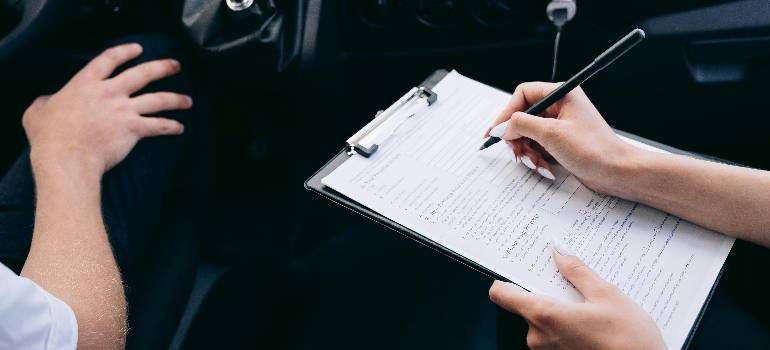 Hands writing on a clipboard during a meeting in a car interior