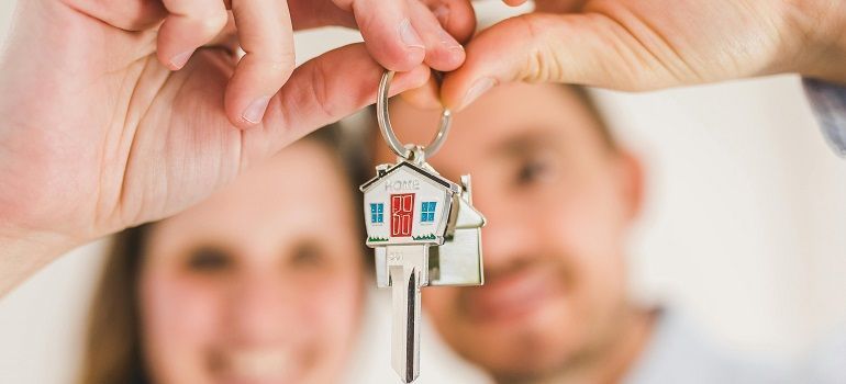 Couple holding keys, Massachusetts vs Connecticut real estate market decision moment
