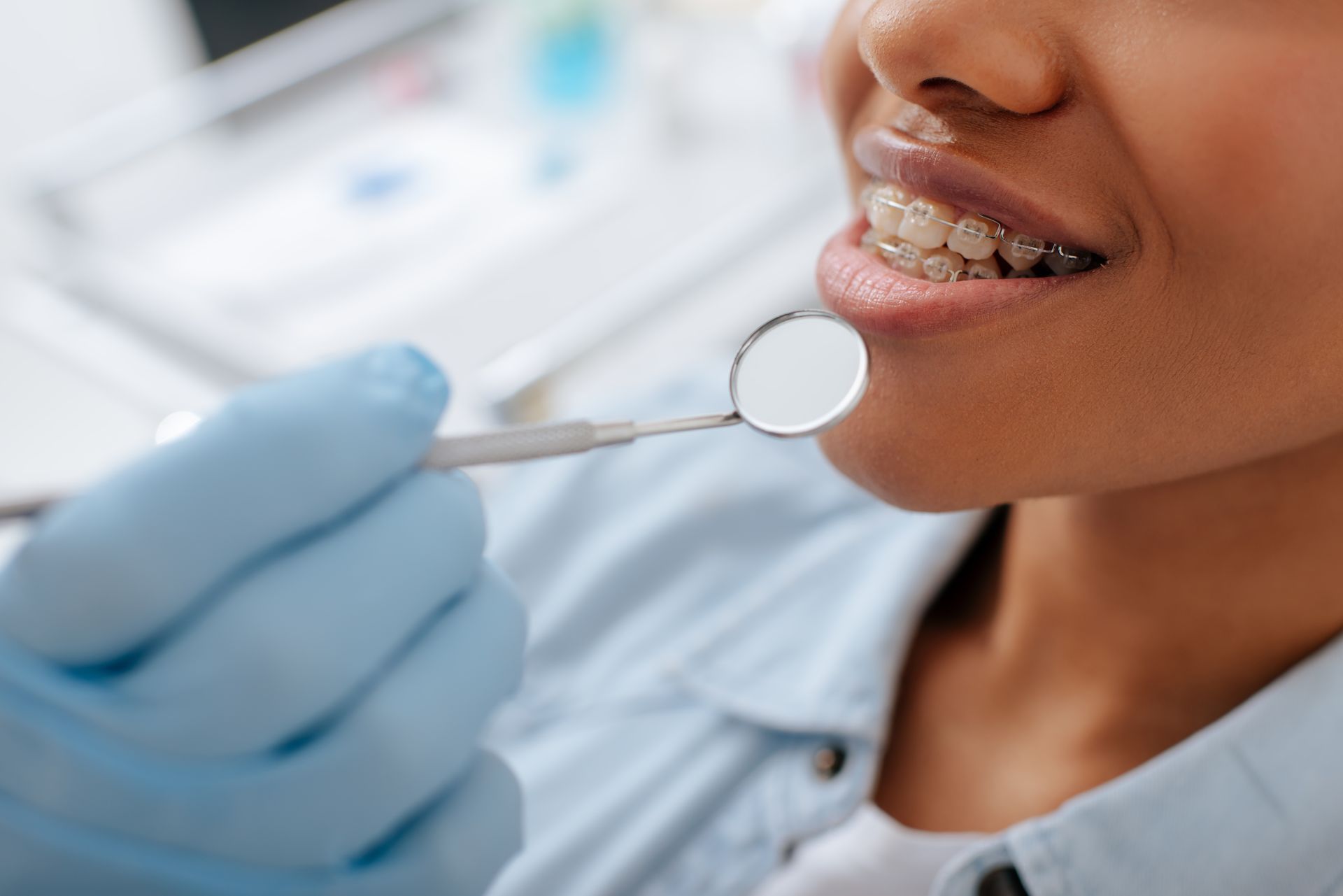 A dental professional uses a mirror tool to check a patient’s teeth during a braces exam.