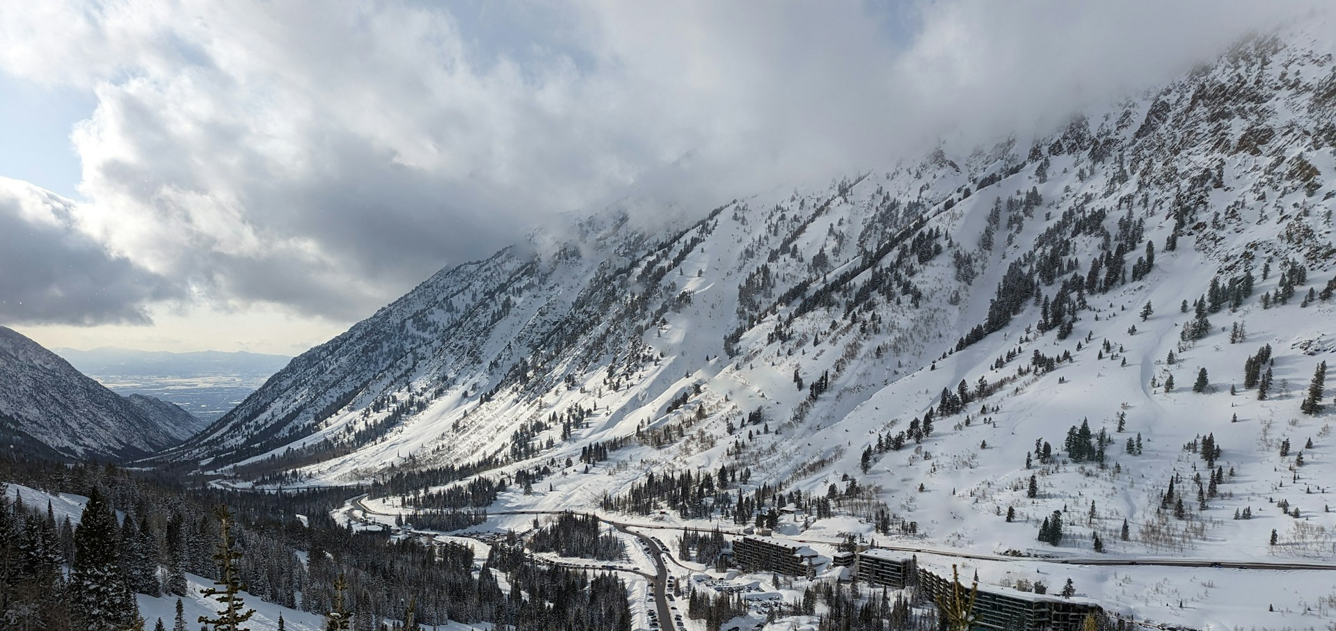 A snowy mountain valley with trees and a road
