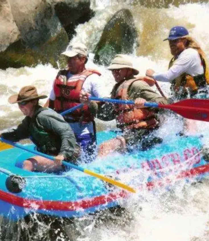 A group of people are rafting down a river in a blue raft