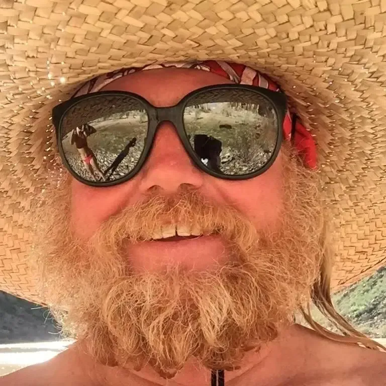 A man with a beard wearing sunglasses and a straw hat