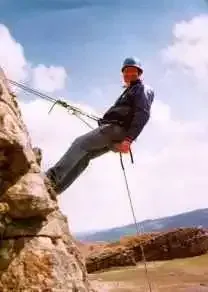 A man is climbing a rock wall with a rope.