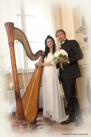 coppia di sposi con bouquet accanto a un'arpa