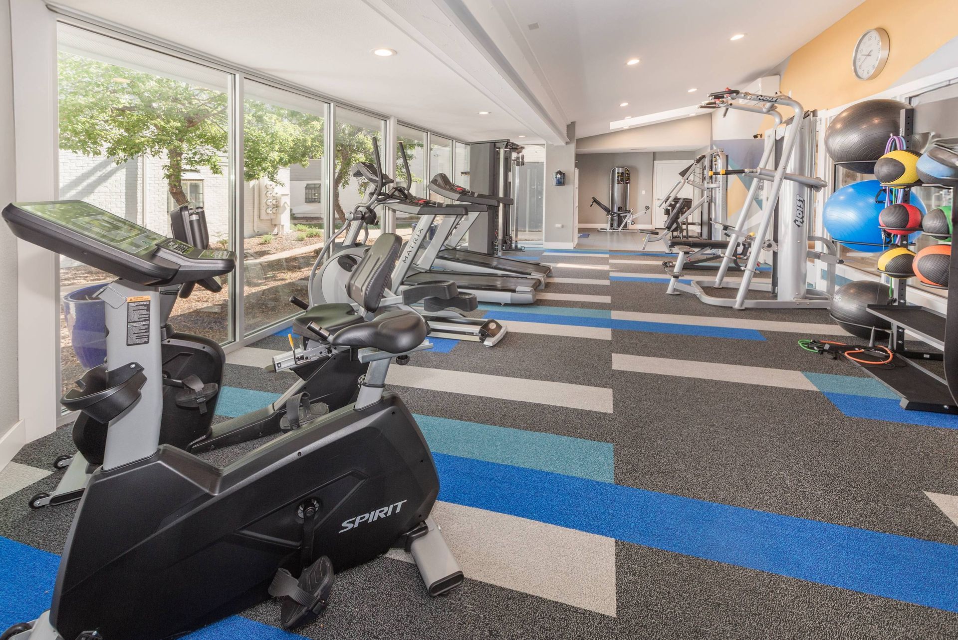On-site gym with treadmills, bikes, and weight equipment by large windows.