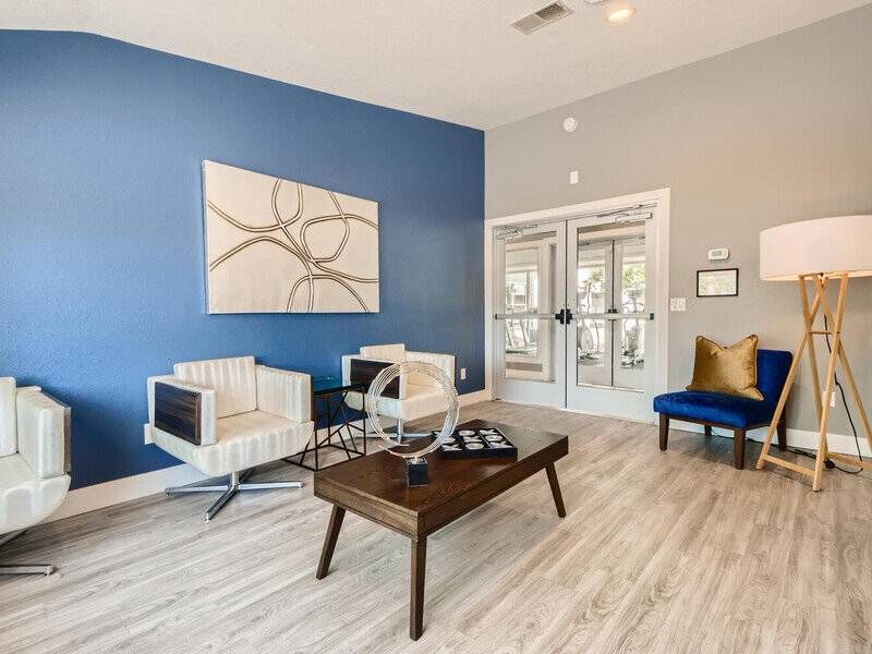 Indoor community lounge with blue accent wall, contemporary seating, and glass entry doors.