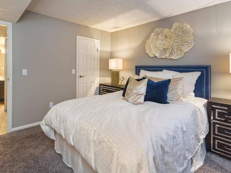 Preserve at City Center apartment with a large bed, blue upholstered headboard, and two nightstands.