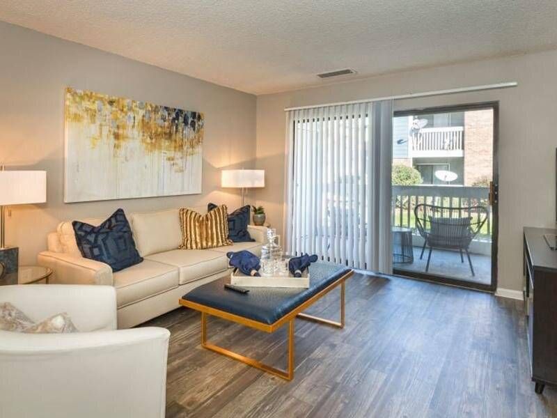 Living room Preserve at City Center apartment with a beige sofa, blue pillows, and sliding glass door to a balcony.
