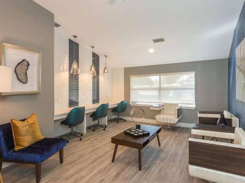 Preserve at City Center communal lounge with work desks, teal chairs, and lounge seating by a large window.