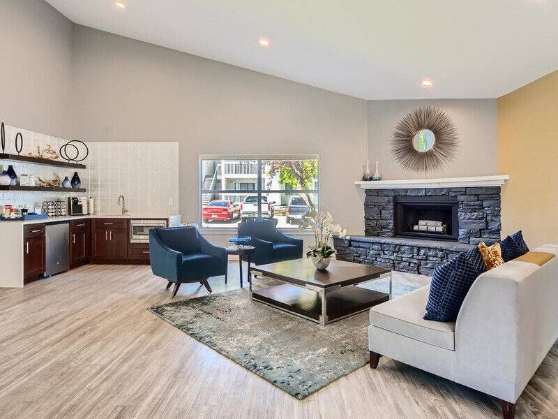 Modern living room at Preserve at City Center with a stone fireplace, seating, and a small kitchenette.