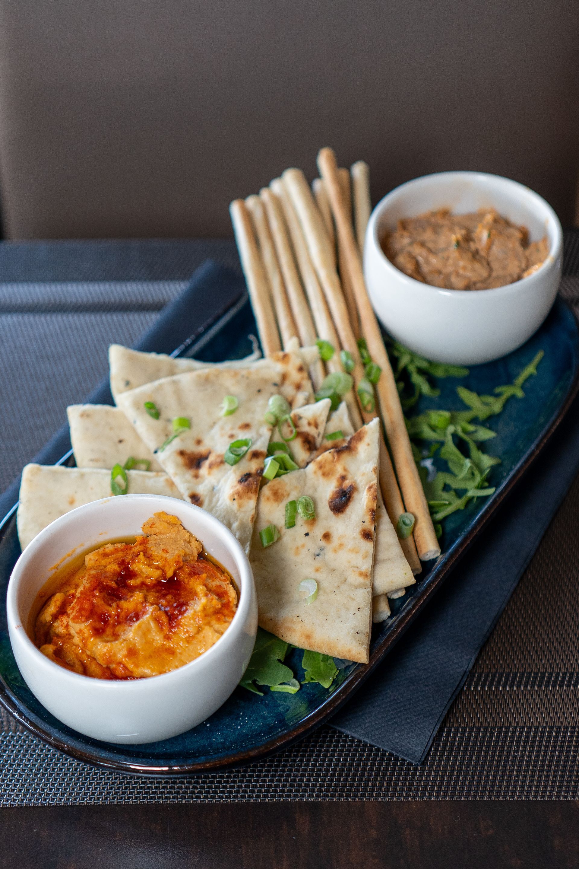 Plateau d'apéritifs avec pain pita, gressins et bols de houmous.