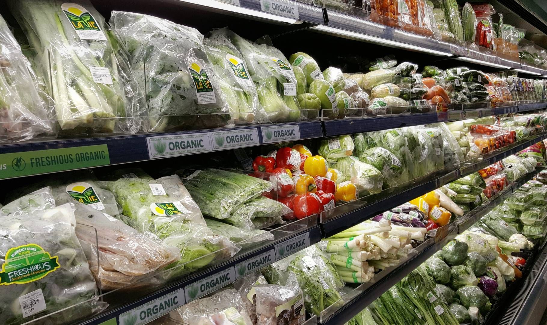 A grocery store aisle filled with lots of fresh vegetables.