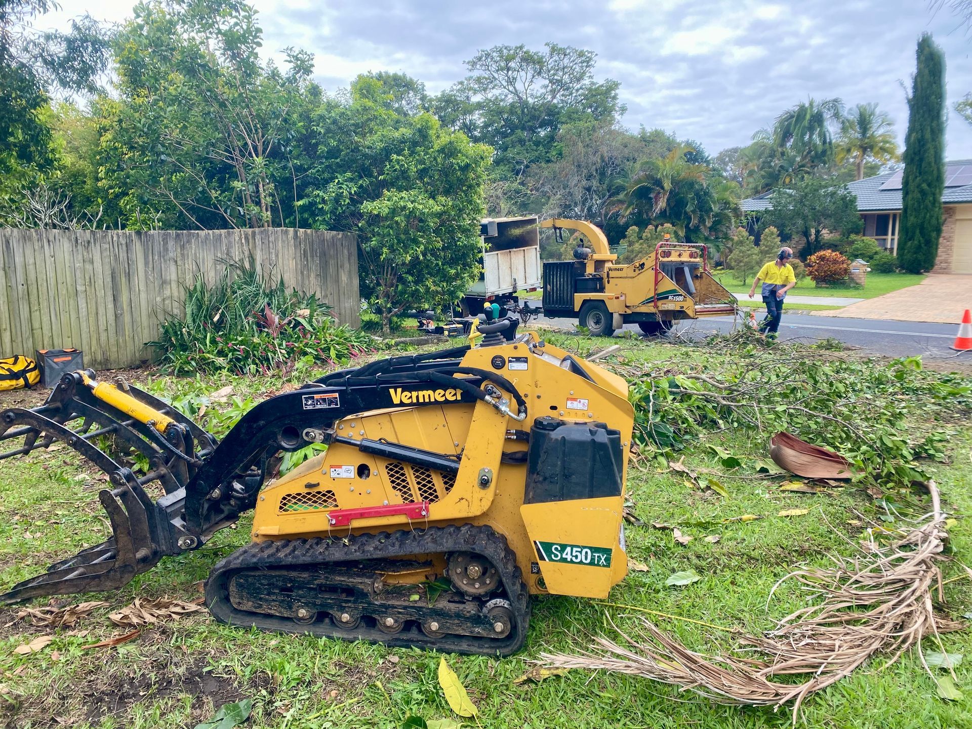 Yellow Mini-excavator and Wood Chipper on Grass, Worker Nearby — AAA Trees On Tweed In Currumbin Valley, NSW