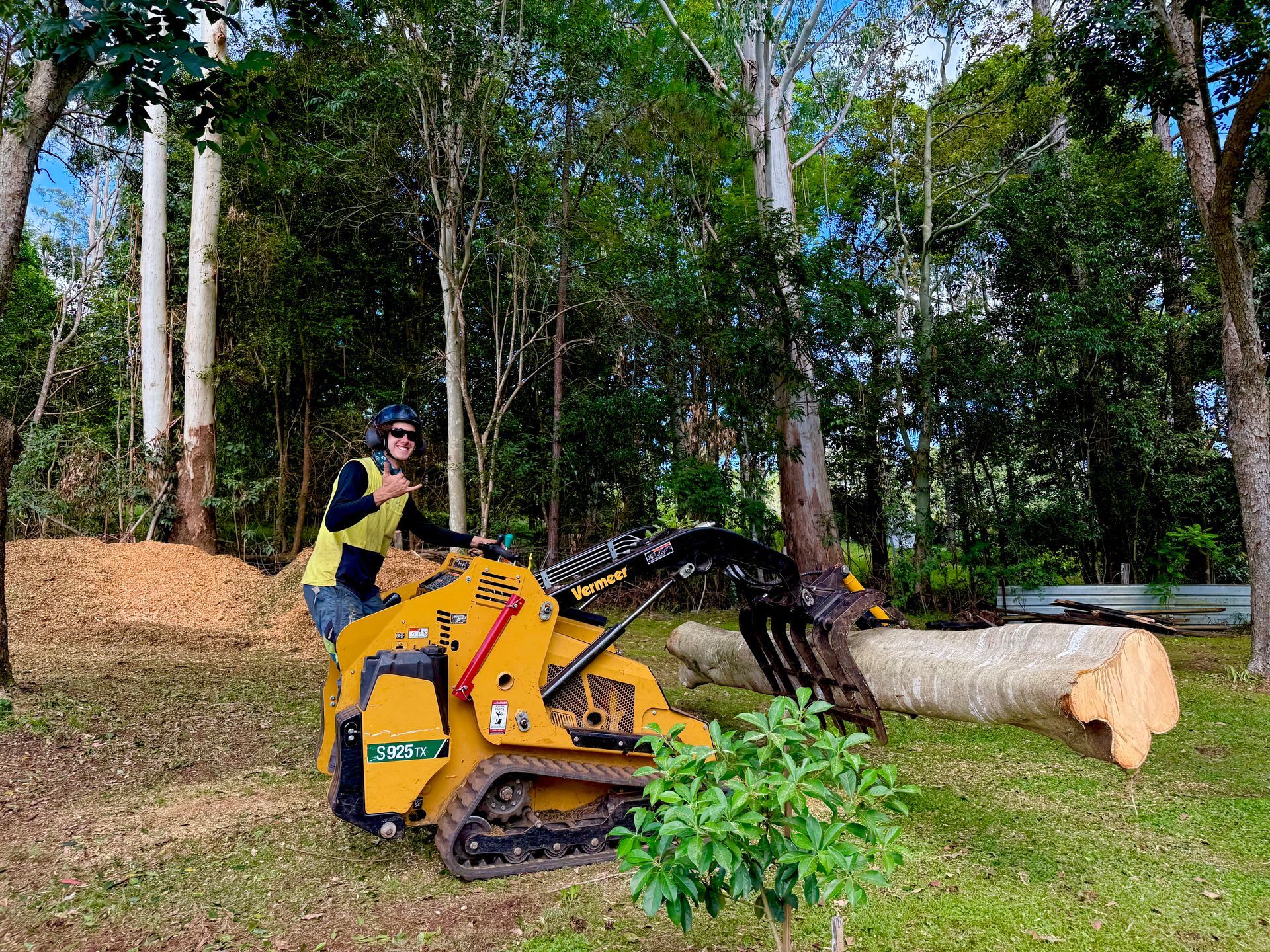 Person Operating a Yellow Mini Skid Steer with Log Grabber — AAA Trees On Tweed in Ballina, NSW