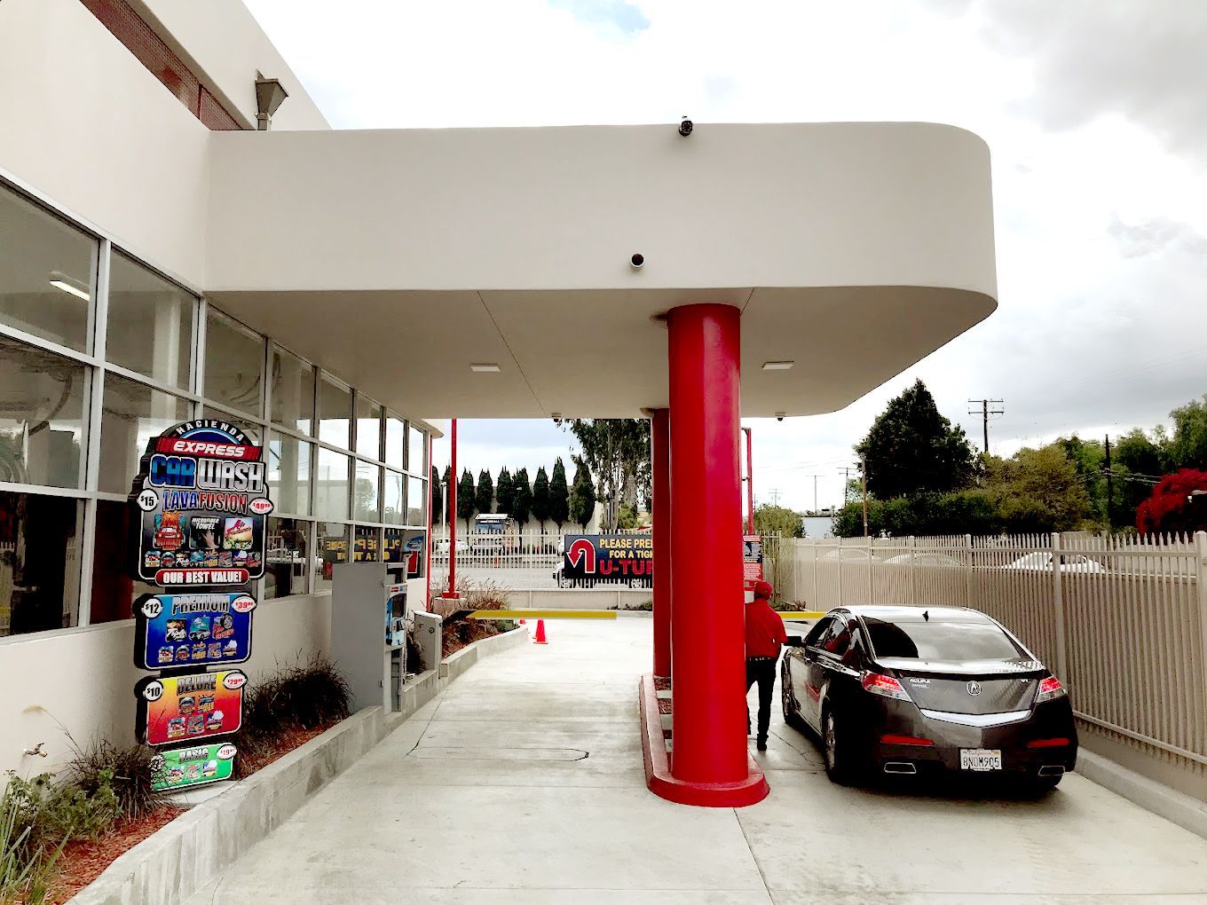 A car is parked under a red pillar at a gas station