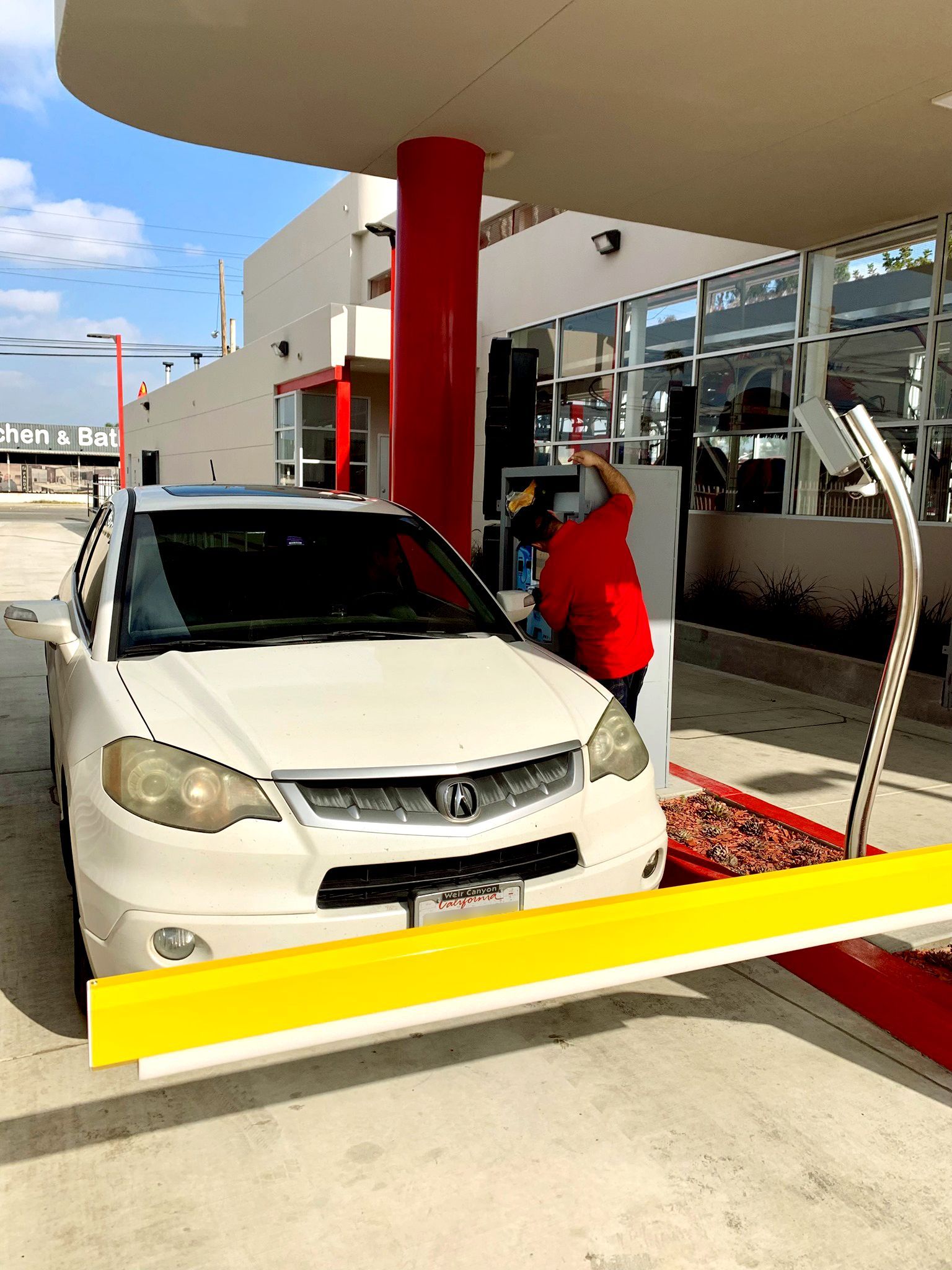 A white car is parked in front of a gas station.