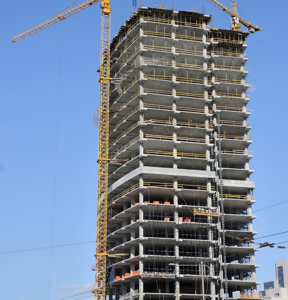 A tall building under construction with a crane in front of it
