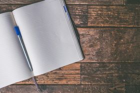 An open notebook with a pen on a wooden table