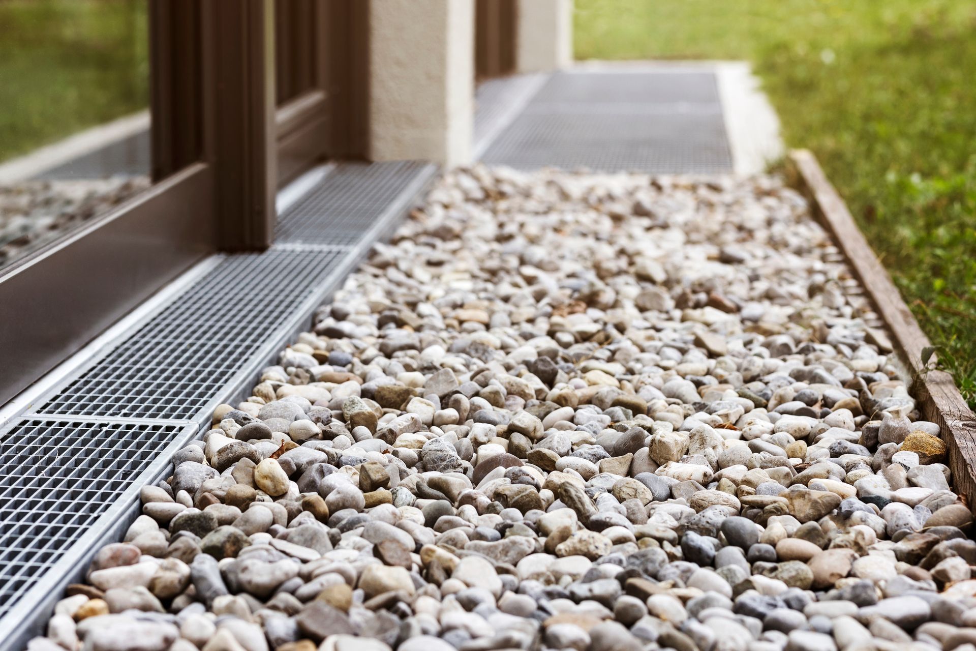 A sidewalk filled with gravel and a metal grate.