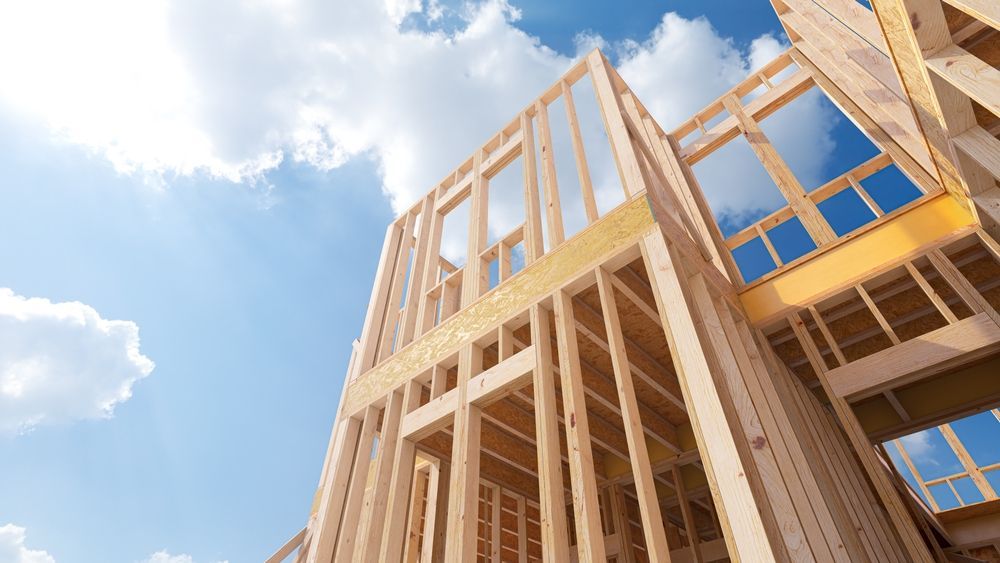 A large wooden building under construction with a blue sky in the background.