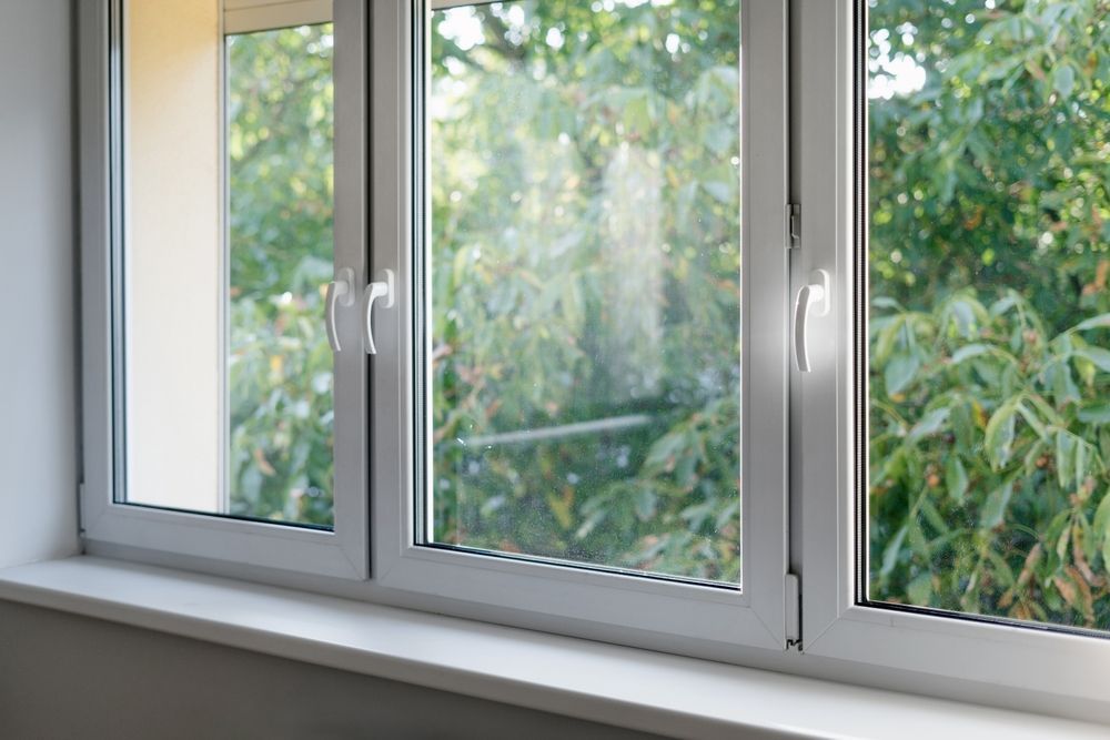 A close up of a white window with a view of trees.