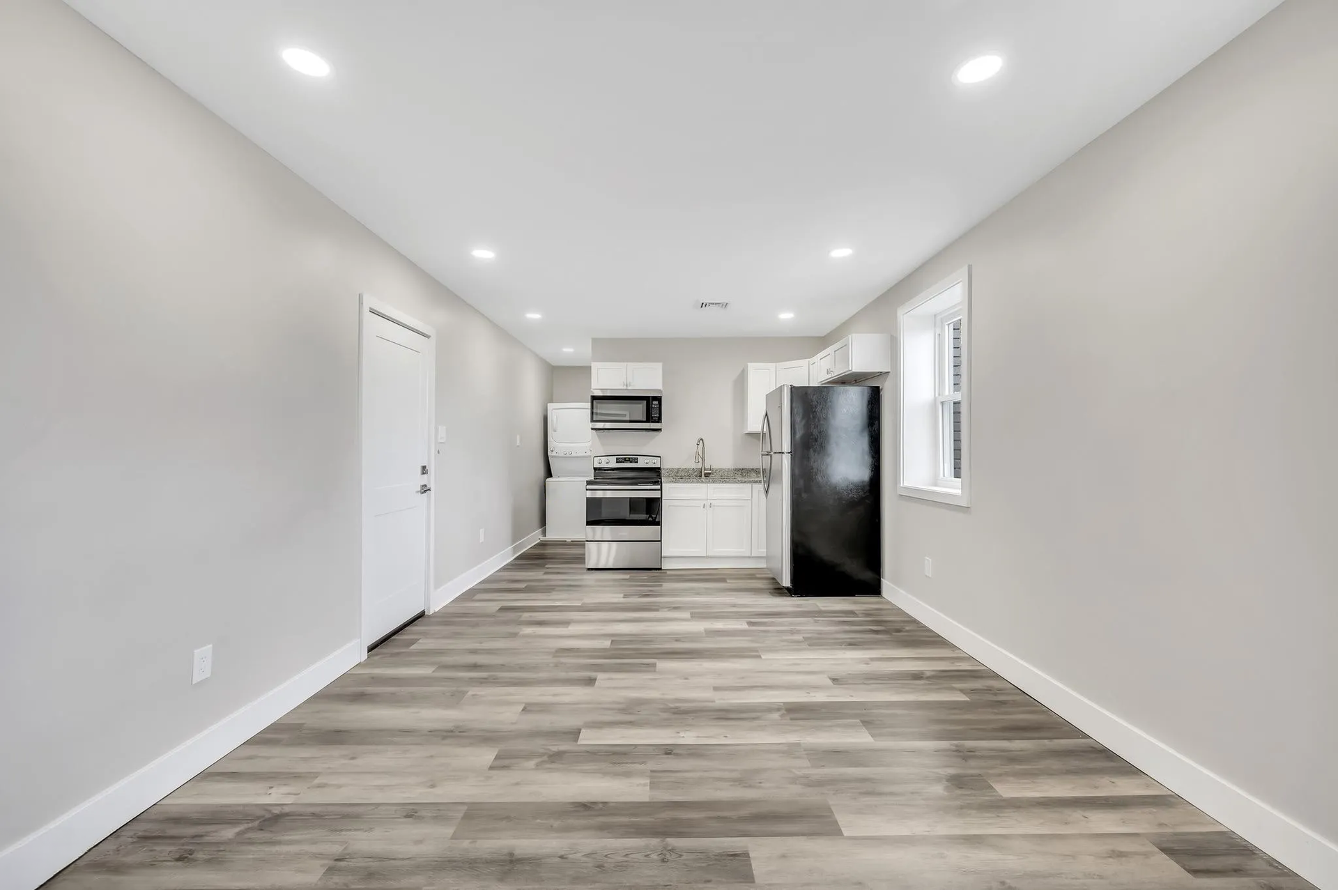 An empty room with a kitchen and a refrigerator