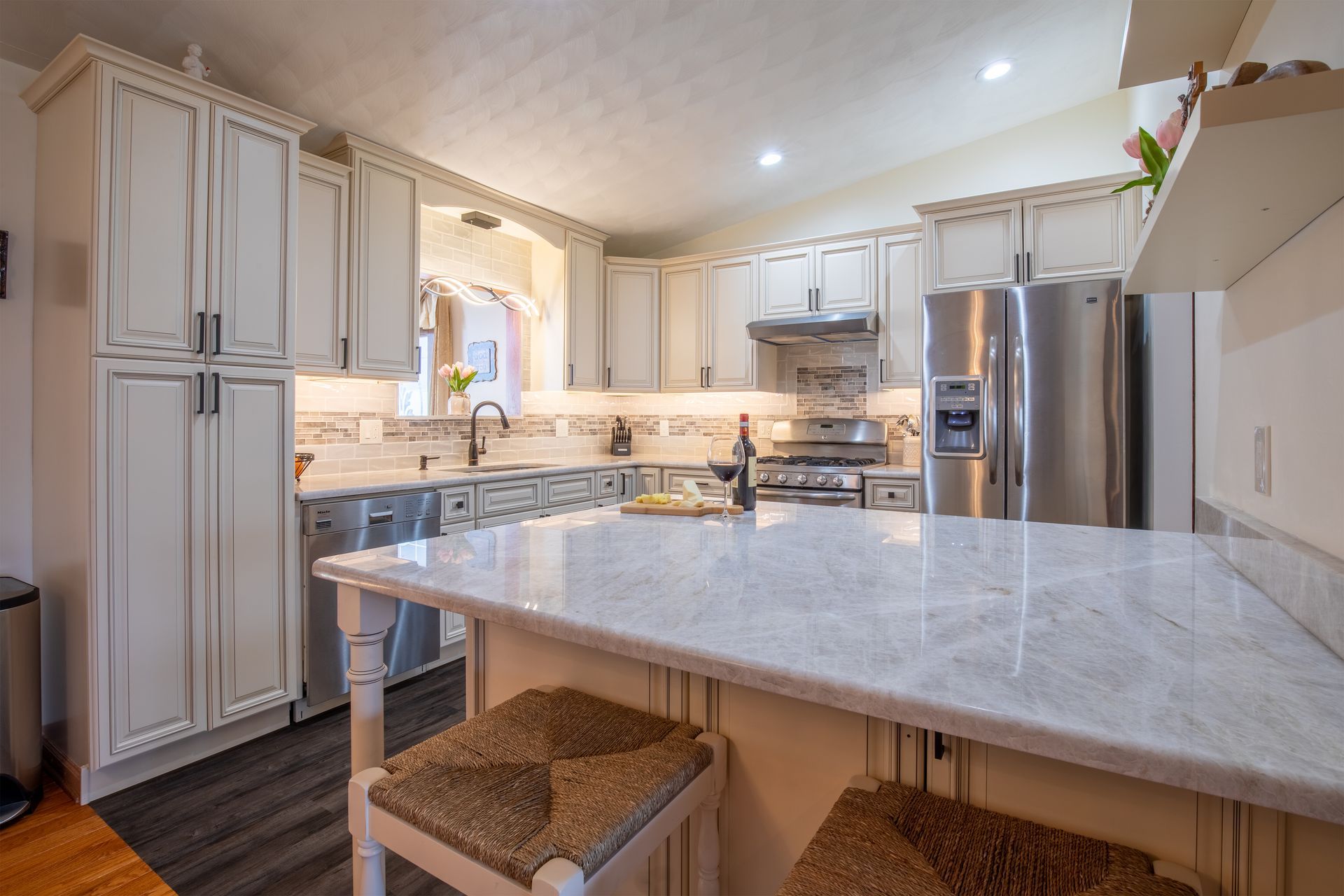 A kitchen with white cabinets , stainless steel appliances , and a large island.