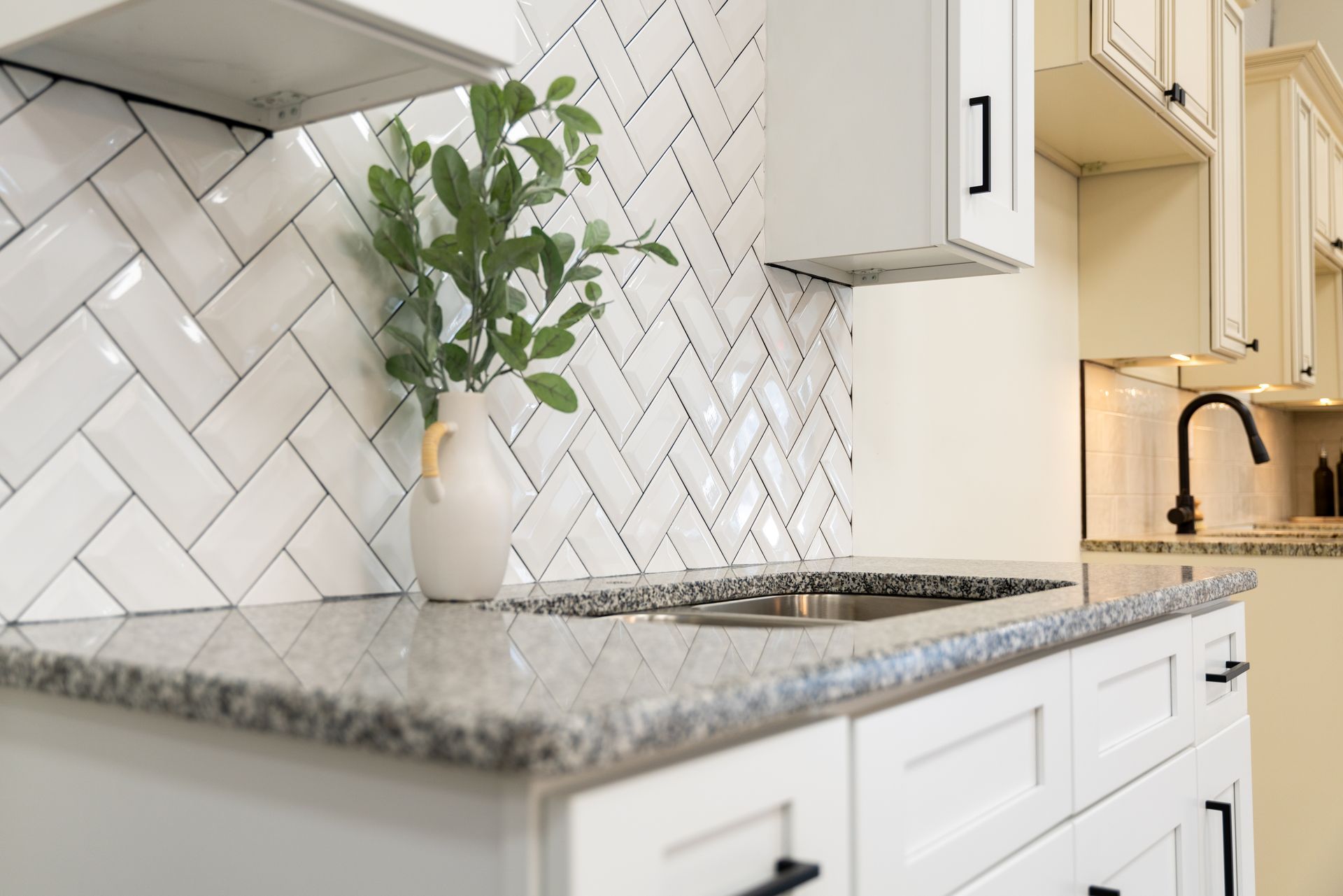 A kitchen with white cabinets , granite counter tops , and a sink.