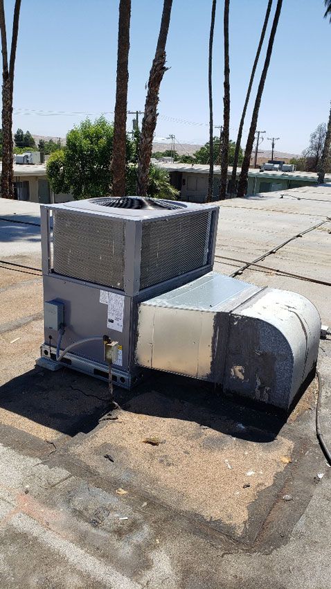 A large air conditioner is sitting on top of a concrete roof.