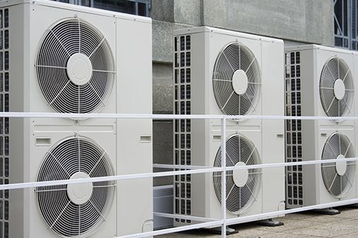 A row of air conditioners sitting next to each other on the side of a building.